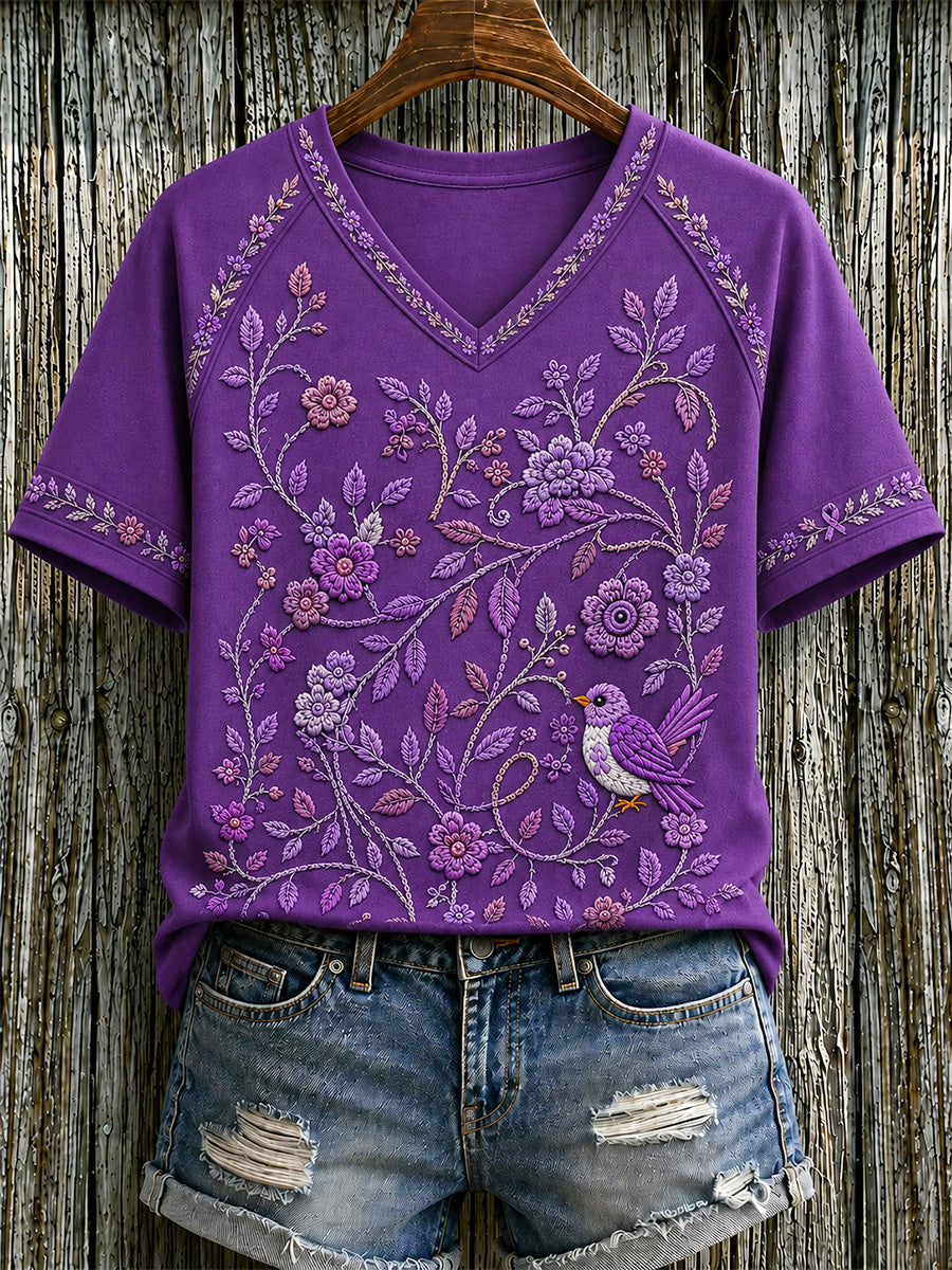 Dame-T-shirt med lilla blomster- og kolibri-print til støtte for alzheimers-håndteringen, med V‑udskæring