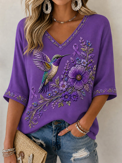 Dame-T-shirt med lilla blomster- og kolibri-print til støtte for alzheimers-håndteringen, med V‑udskæring