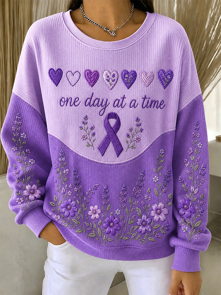 Damebluse i lilla med blomstermønster og oplysning om Alzheimers, støttende print, ribbet, rund hals