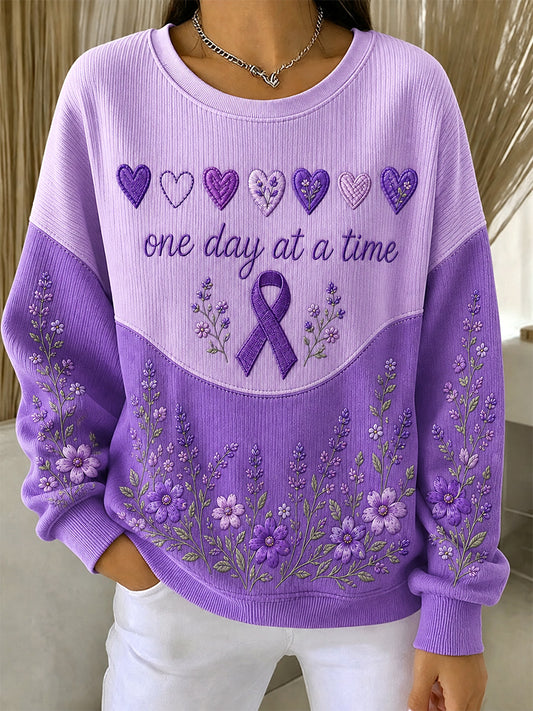 Damebluse i lilla med blomstermønster og oplysning om Alzheimers, støttende print, ribbet, rund hals
