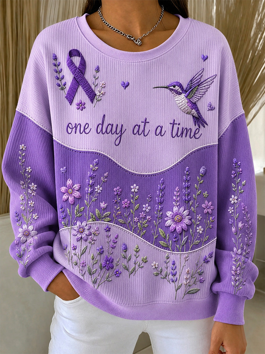 Damebluse i lilla med blomstermønster og oplysning om Alzheimers, støttende print, ribbet, rund hals