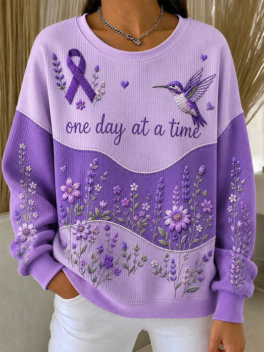 Damebluse i lilla med blomstermønster og oplysning om Alzheimers, støttende print, ribbet, rund hals