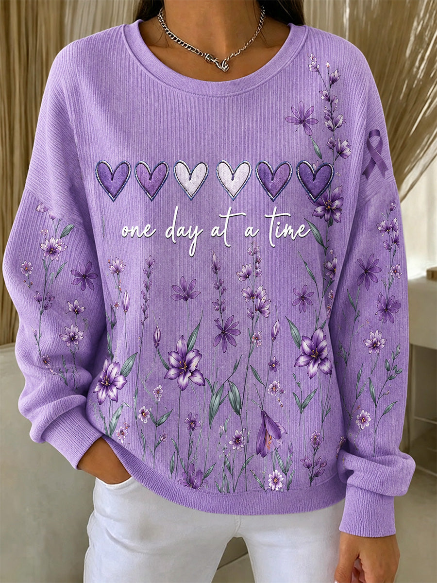 Damebluse i lilla med blomstermønster og oplysning om Alzheimers, støttende print, ribbet, rund hals