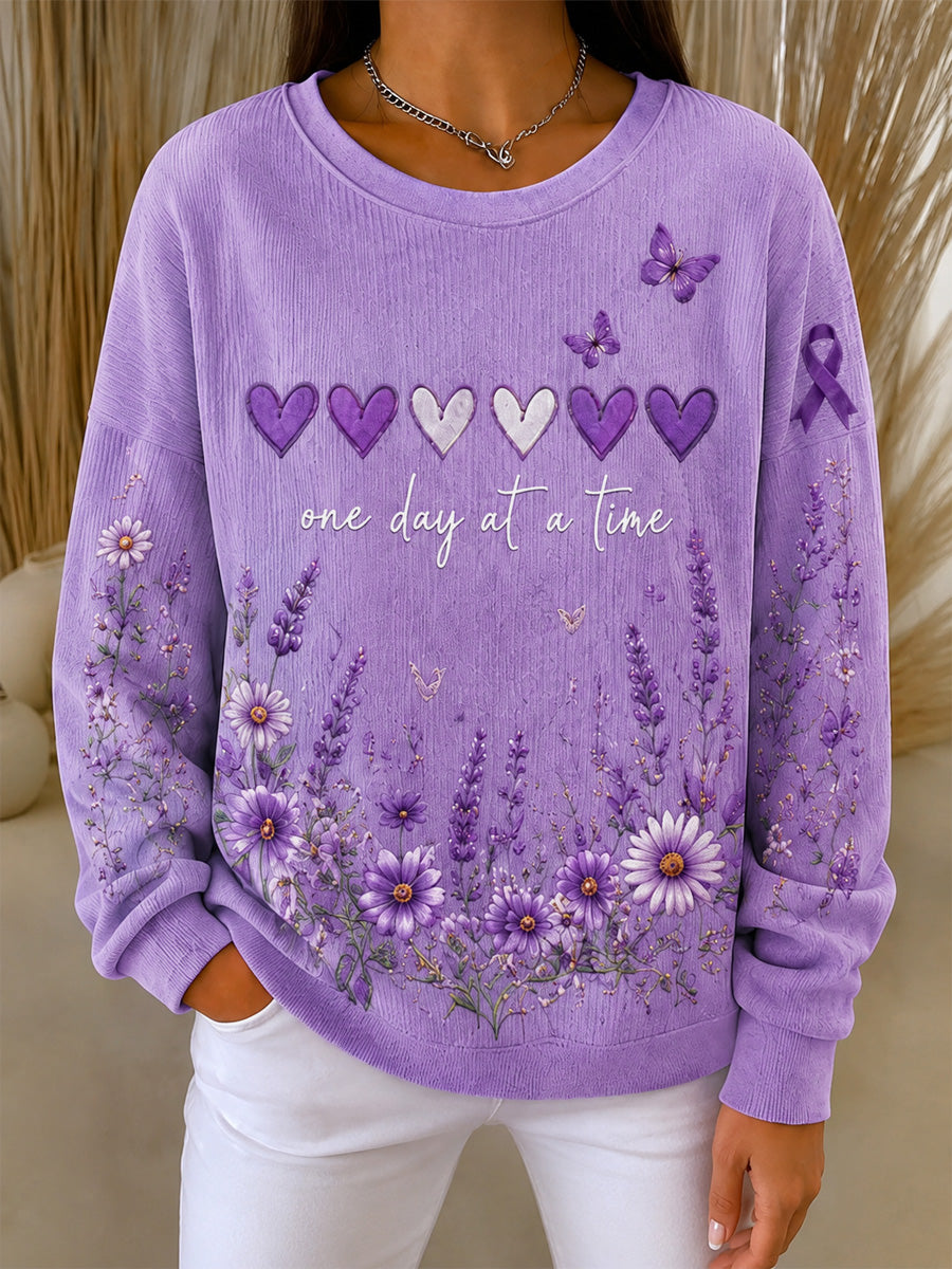 Damebluse i lilla med blomstermønster og oplysning om Alzheimers, støttende print, ribbet, rund hals
